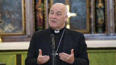 The Archbishop of York Stephen Cottrell wearing a purple clerical shirt and dog collar with a suit