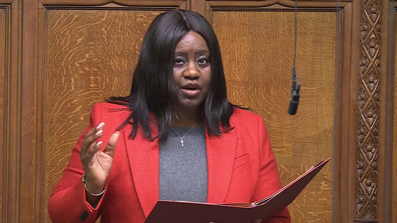 Marsha de Cordova MP wearing a red jacket holding a folder as she speaks in the House of Commons