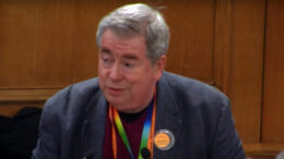 Clive Billenness, wearing a grey suit, speaking at the General Synod